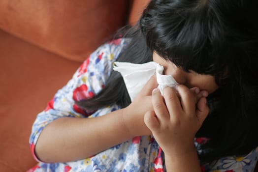 Sick child with flu blow nose with napkin