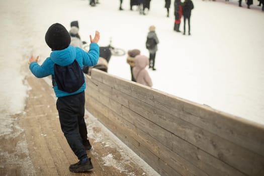 Child rides down slide. Winter game. Boy rides on his feet on ice. Winter entertainment.