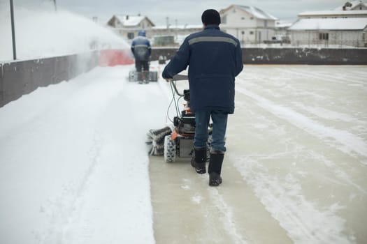 Snow removal on ice. Cleaning of stadium. Worker prepares ice for ice skating.