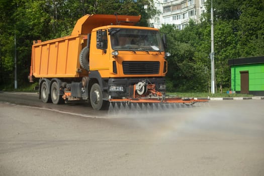 Harvesting equipment on road. Road cleaning. Watering road with water. Orange Municipal Vehicles.