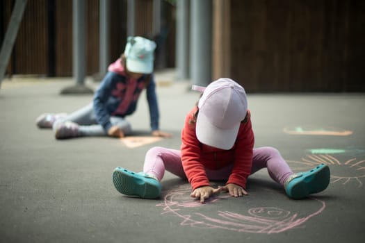 Children draw on asphalt. Drawing in crayons. Children's drawing on street. Creativity in park.