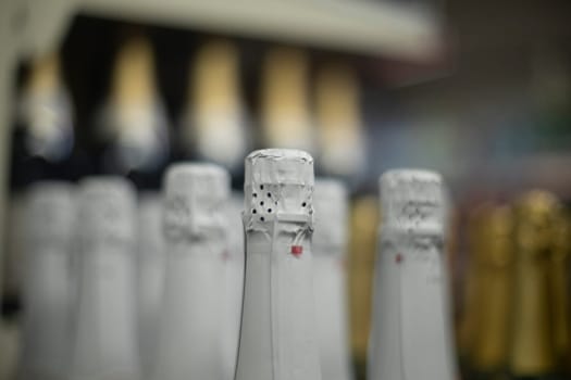 Champagne in shop. Bottle of alcohol. Drinks on counter. Boots stand in row.