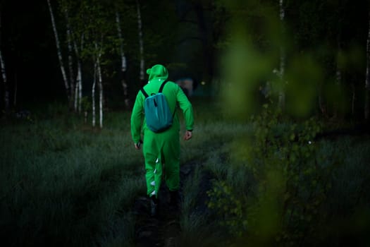 Guy in crocodile costume comes out of swamp. Funny character at festival in woods. Man in green suit.