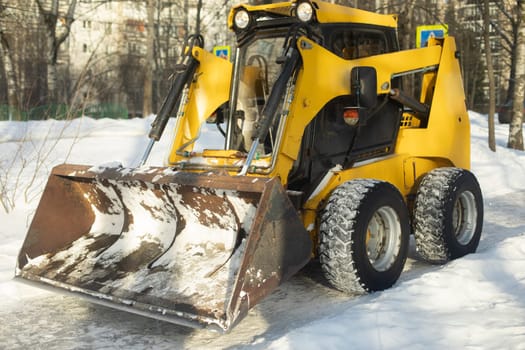 Snow harvesting equipment. A tractor with a bucket. Snow removal in the city. Heavy duty machine to work with.