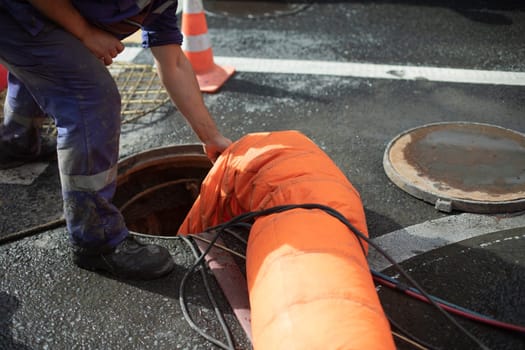 Sewer repair. Pumping waste from hatch. Open hatch. Worker controls air supply. Sewerage accident.