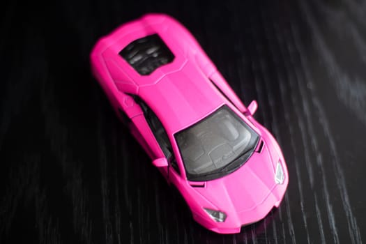 Sport car. Toy car model. High-speed transport. Exclusive racing car replica. Action figure macro. Side view. Dark background.
