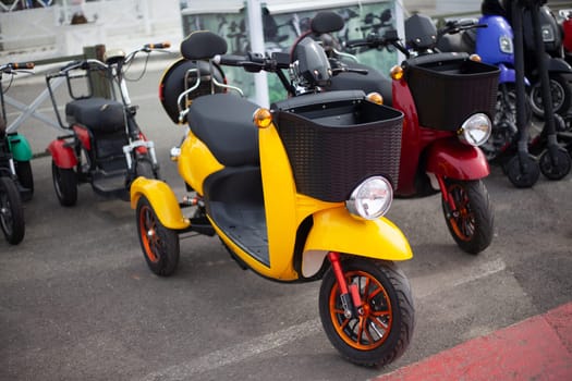 Moto electric vehicles are in a row. Electric bike rental. Headlights at two wheeled vehicles. Motorcycle sale. Mass parking of vehicles. Modern urban way of driving.