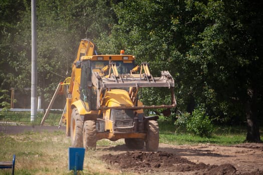 A tractor digs the ground. The work of the tractor with the bucket. Soil cleaning. Start of construction works.