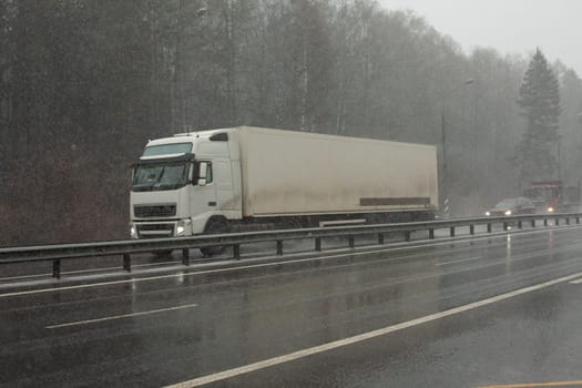 Truck on the highway. Cargo transportation between cities. Big car on the road. The road outside the city.