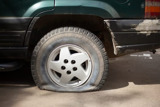 Deflated car wheel. Car is in parking lot. Transport details.