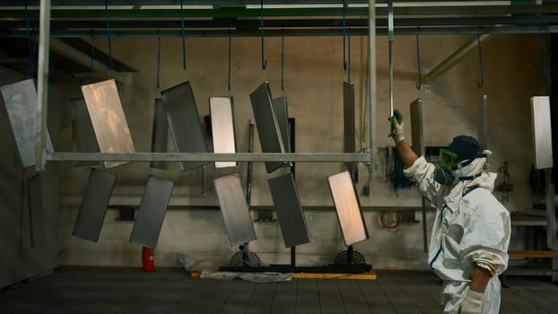 Worker pushing line of painted metal sheets into the drying chamber. Creative. Steel production plant