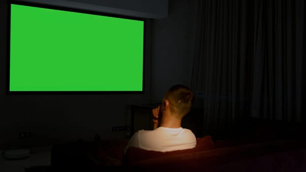 Viewing on a projector in a closed room. Media. A man looking into a green screen that is shown on a large screen. High quality 4k footage