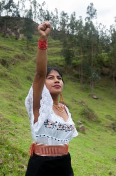 indigenous feminist girl with her arm raised and her hand in the form of a fist looking towards the sky as a sign of empowerment. women's day. High quality photo
