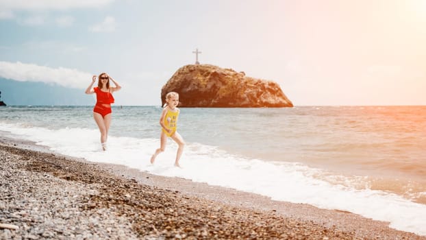 Happy loving family mother and daughter having fun together on the beach. Mum playing with her kid in holiday vacation next to the ocean - Family lifestyle and love concept.