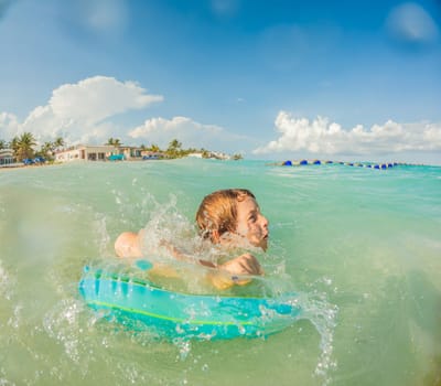 Joyful boy plays in the sea, creating playful splashes and enjoying the waves.