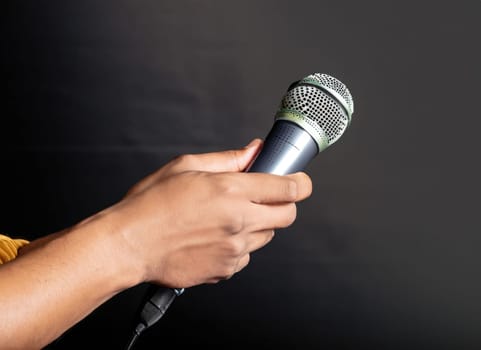  hand with microphone on gray background, close o