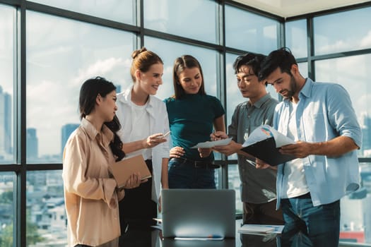 Asian project manager uses laptop displayed data analysis while professional business team brainstorming marketing idea at business meeting. Working together,sharing idea, planing strategy. Tracery.