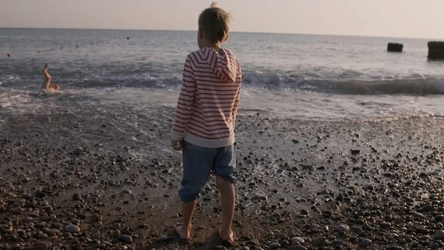 Rear view of a boy on pebble beach on a summer day. Creative. Concept of vacation