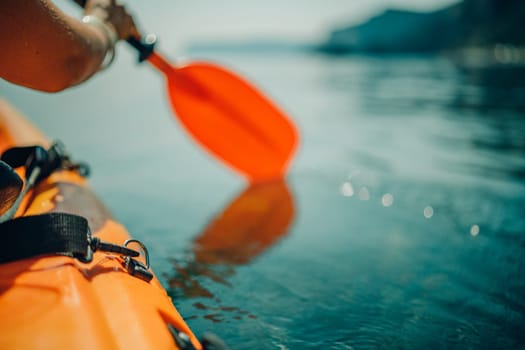 Kayak paddle sea vacation. Person paddles with orange paddle oar on kayak in sea. Leisure active lifestyle recreation activity rest tourism travel.