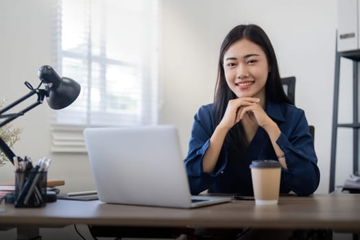 Smiling woman sitting at her desk in office and coffee. Happy business woman sitting in office.