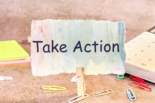 Business concept. Phrase TAKE ACTION written on paper next to scattered paper clips, calculator, adhesive paper.