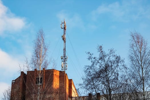 Communication antenna on the roof of a multistory building against the blue sky