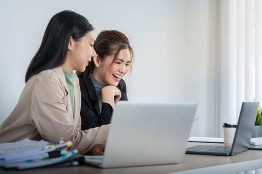 Business woman talking to female coworker, showing project results at meeting. analyze planning and finance statistics and investment market at office in office using pc laptop.