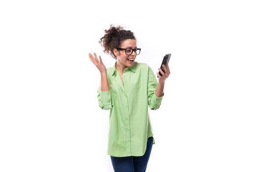 charming young slender female model dressed in a light green shirt chatting in a mobile phone on a white background. people lightstyle concept.