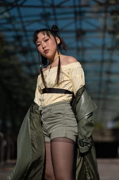 A beautiful Asian woman in shorts and a green leather coat comes out of the subway