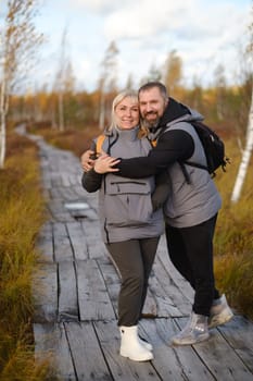 People in boots stand hugging on a wooden path in a swamp in Yelnya, Belarus.