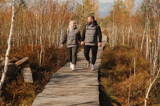Two tourists walk along a wooden path in a swamp in Yelnya, Belarus.