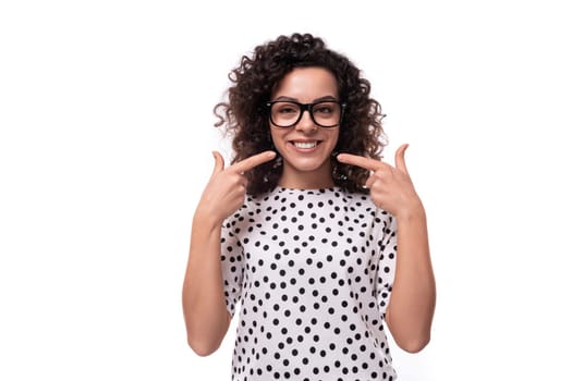 young caucasian businesswoman with curly hair dressed in a blouse with polka dots on a white background.