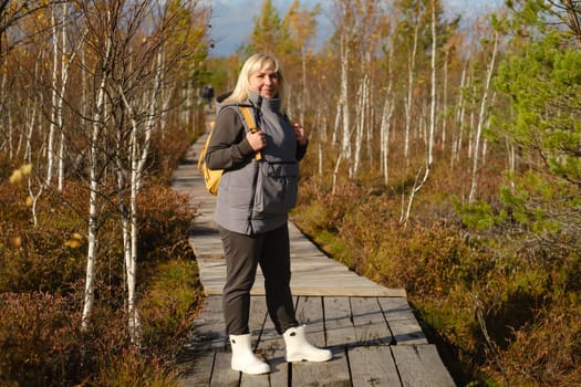 A woman stands on a wooden path in a swamp in Yelnya, Belarus.