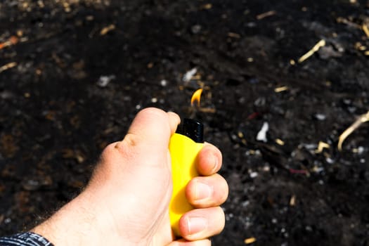 Burnt metal lighter in ashes. Consequences of fire. Close-up.