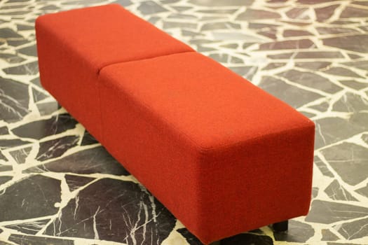 Red ottoman. Sitting in theater. Place to relax. Comfortable shop. Interior details.