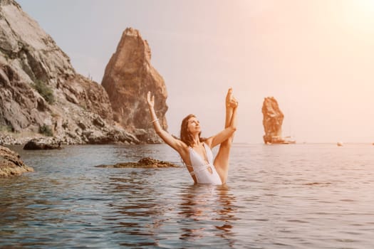 Young woman with black hair, fitness instructor in pink sports leggings and tops, doing pilates on yoga mat with magic pilates ring by the sea on the beach. Female fitness daily yoga concept