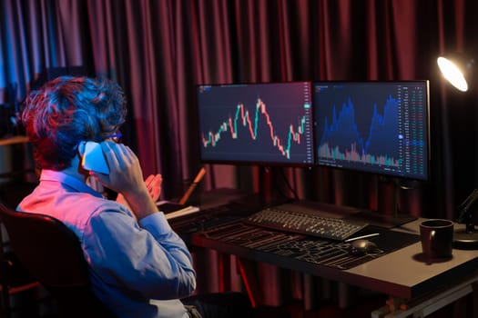 Young business trader calling to broker, consulting profit currency rate investment on global market online on pc screen in real time at neon light modern office. Concept of stock exchange. Gusher.