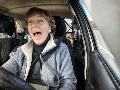 Terrified female driver a second before the accident. Scared middle-aged adult woman holds the steering wheel of car. Frightened Lady girl who is owner or rent a car for travel