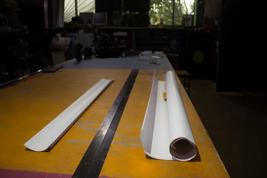 Roll of paper. Cutting film. Big lineup. Table in advertising workshop. Preparation of project.