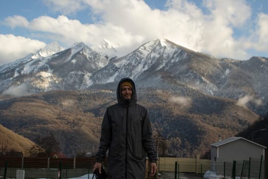 Guy in background of mountains. Man on road in mountains. Travel details. Snowy peaks.