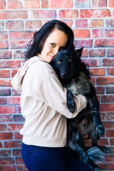 Happy lady in a casual wear hugging purebred pet dog, mudi with owner over studio background.