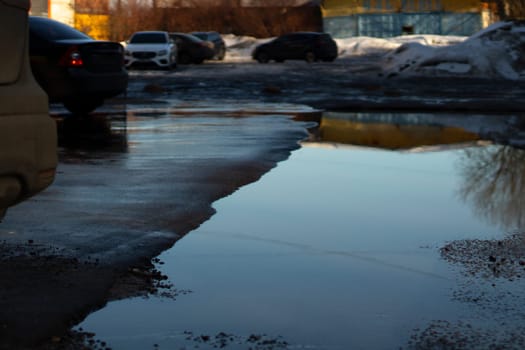 Puddle in road. Wet asphalt. Spring weather. Melting snow.