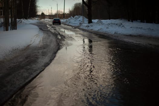 Wet road. Puddle on pavement. Water on highway. Car left on road.