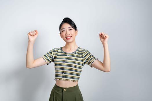 Young asian woman raising arms while smiling and screaming to celebrate after successfully work