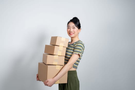 Happy asian woman holding pile of boxes, concept of delivery, shopping or business, white background