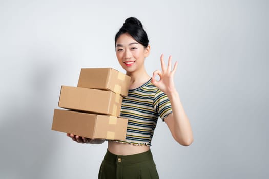 Young asian woman moving to a new home cheerful and confident showing ok gesture.