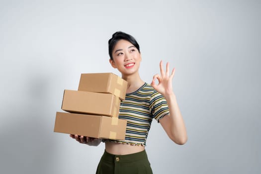 Portrait of young Asian business woman with boxes showing OK sign