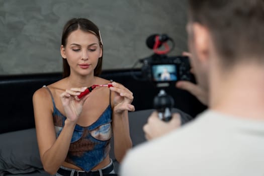 Man filming video on young woman making beauty and cosmetic tutorial video content for social media. Beauty blogger smiles to camera while showing how to beauty care to audience or follower. Unveiling