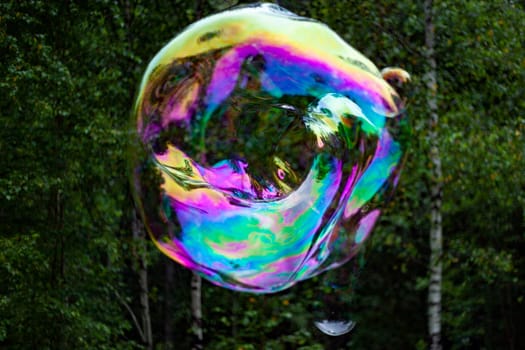 Big bubble on street. Thin soap film. Soap balloon. Sphere in air.