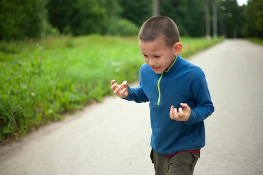 Child is angry. Boy threatens. Schoolboy swears in street. Negative emotions in child.